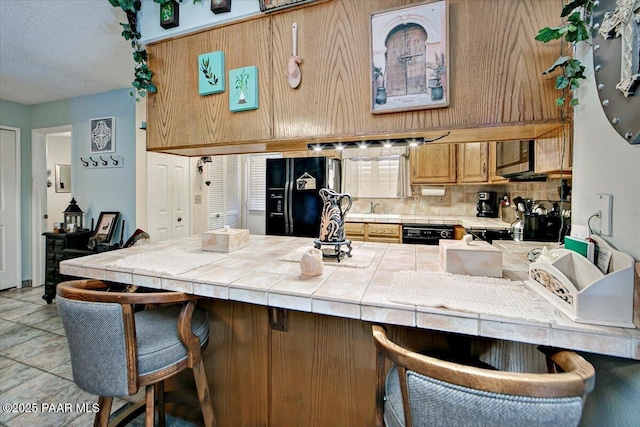 435 Jasmine Ln, Prescott, AZ 86301 - kitchen with tile countertops, a kitchen breakfast bar, a peninsula, and black fridge