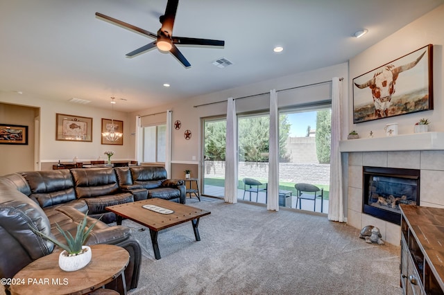 living room featuring a tiled fireplace, ceiling fan, and light carpet