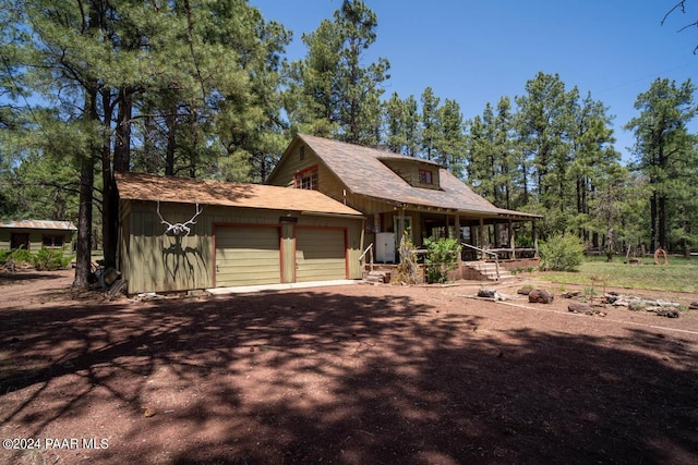 rustic home with covered porch, dirt driveway, and a garage