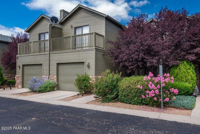 view of front of home featuring a garage, driveway, and a balcony