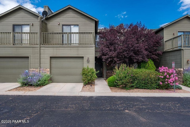 view of front of house featuring a balcony, driveway, and an attached garage