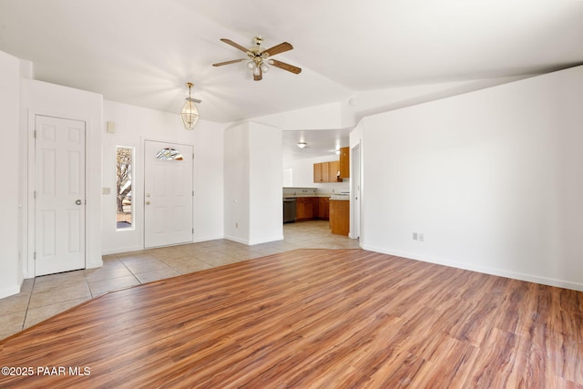 unfurnished living room with vaulted ceiling, light tile patterned flooring, a ceiling fan, and baseboards