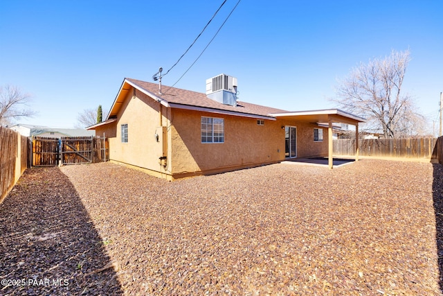 back of property with a gate, a fenced backyard, central AC, stucco siding, and a patio area