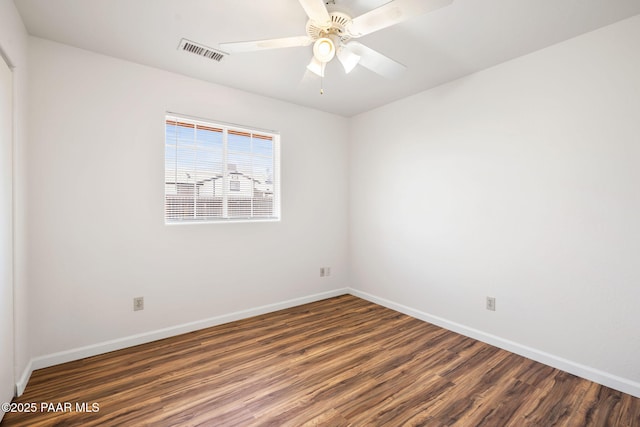 spare room with ceiling fan, visible vents, baseboards, and wood finished floors