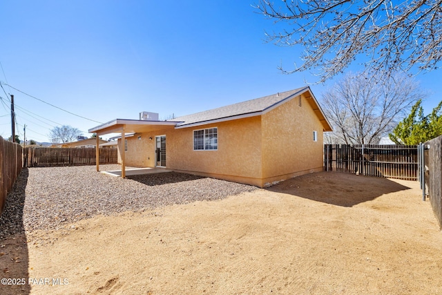 rear view of property with stucco siding, a patio, and a fenced backyard