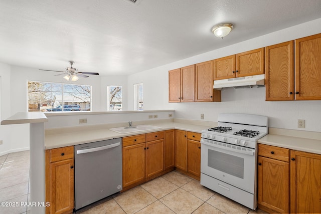 kitchen featuring under cabinet range hood, white range with gas cooktop, a peninsula, stainless steel dishwasher, and a sink