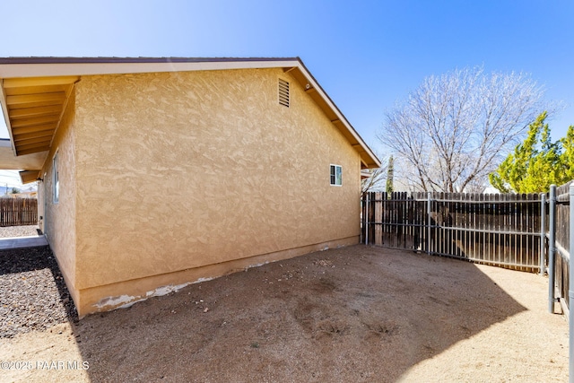 view of side of property featuring stucco siding, a patio, and fence