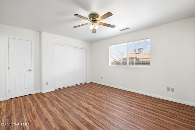 unfurnished bedroom with wood finished floors, visible vents, a closet, and baseboards