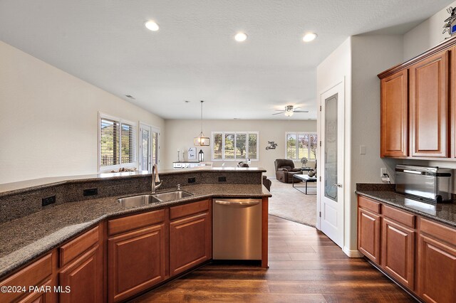 kitchen with dark hardwood / wood-style flooring, stainless steel dishwasher, sink, dark stone countertops, and hanging light fixtures