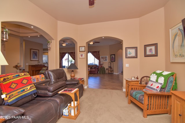 carpeted living area with ceiling fan, arched walkways, and tile patterned floors
