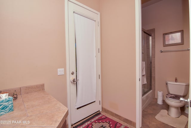 full bath with toilet, tile patterned flooring, and combined bath / shower with glass door