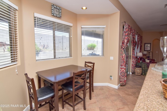 dining room featuring light tile patterned flooring, baseboards, and arched walkways