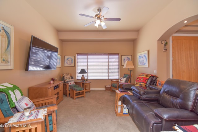 living area with arched walkways, ceiling fan, and light carpet