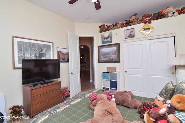 tiled bedroom featuring arched walkways, a closet, and ceiling fan
