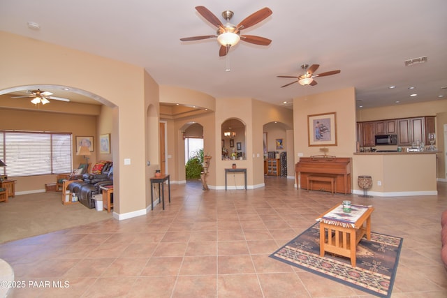 living room featuring arched walkways, ceiling fan, light tile patterned floors, recessed lighting, and baseboards