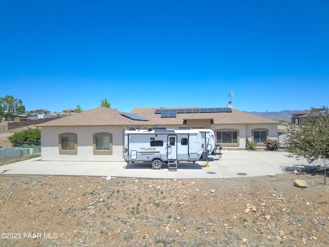 rear view of property featuring stucco siding and roof mounted solar panels