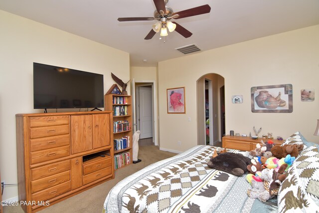 carpeted bedroom featuring arched walkways and a ceiling fan