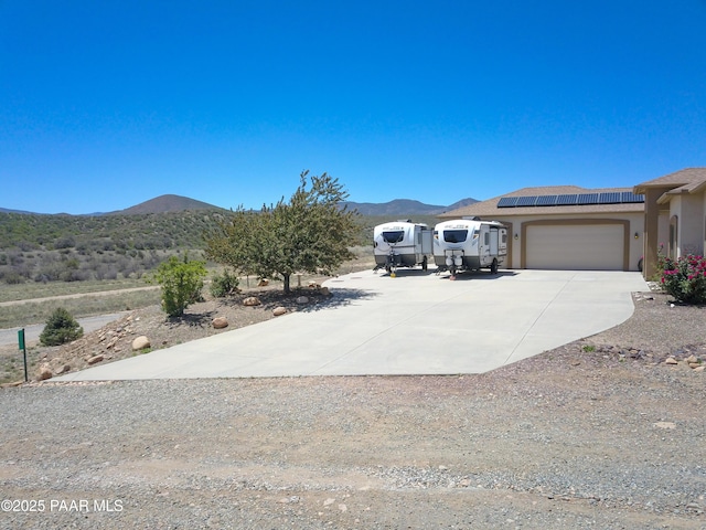 view of yard with concrete driveway, a mountain view, and a garage