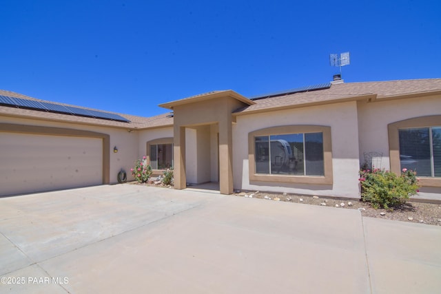 single story home with solar panels, stucco siding, and driveway
