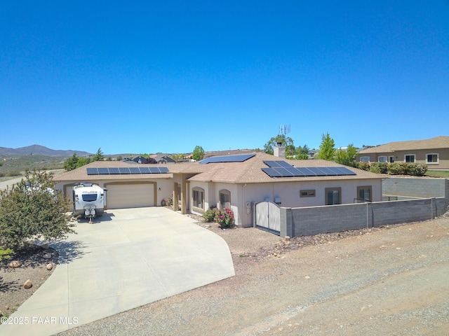 view of front of house with a garage, stucco siding, roof mounted solar panels, and concrete driveway
