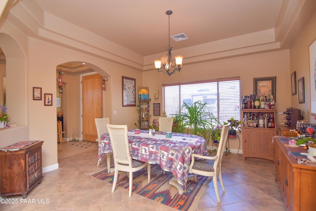 dining space with arched walkways, a raised ceiling, and light tile patterned flooring