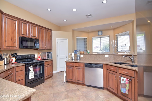 kitchen featuring black appliances, a sink, brown cabinetry, recessed lighting, and light tile patterned flooring