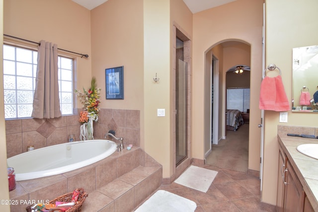ensuite bathroom with vanity, a shower stall, a garden tub, tile patterned flooring, and baseboards