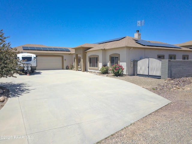 view of front of house featuring a gate, stucco siding, roof mounted solar panels, and a garage