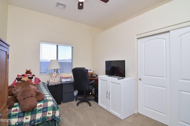 bedroom with light carpet, an office area, and a ceiling fan