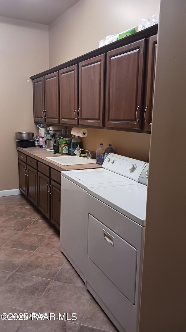 washroom featuring cabinet space, washing machine and dryer, and baseboards