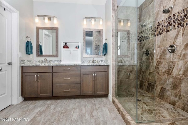 bathroom featuring wood-type flooring, vanity, and a tile shower