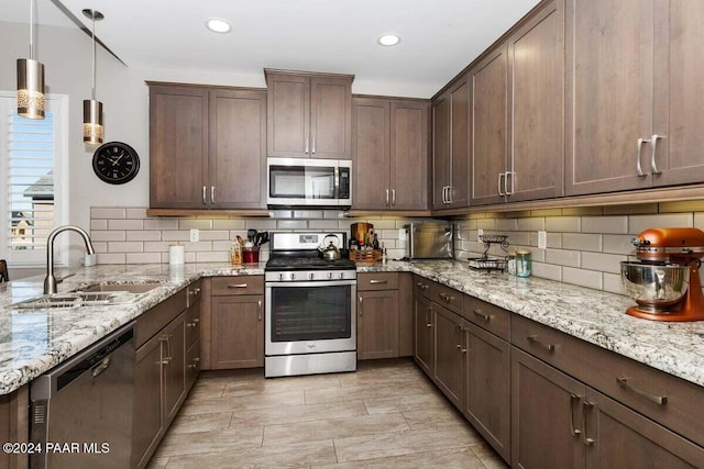 kitchen with decorative backsplash, pendant lighting, stainless steel appliances, and sink