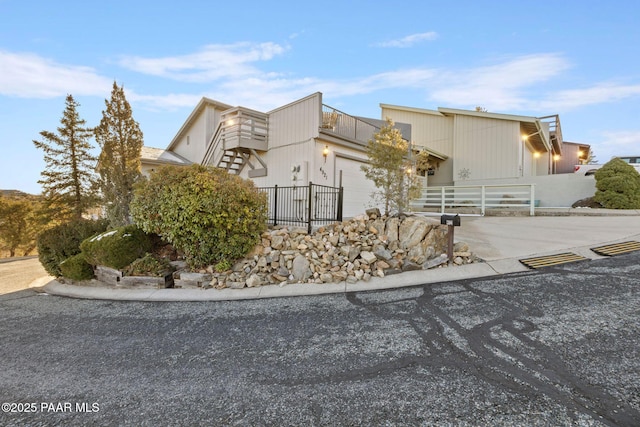 view of front facade with concrete driveway, an attached garage, and fence