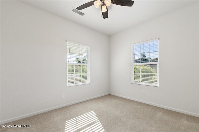 spare room featuring light carpet, plenty of natural light, and baseboards