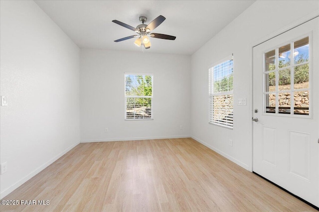 empty room with light wood-type flooring, a ceiling fan, and baseboards