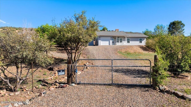 ranch-style house featuring a gate, dirt driveway, a garage, and fence