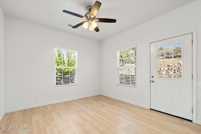 empty room with light wood-type flooring, healthy amount of natural light, baseboards, and a ceiling fan
