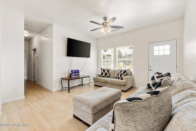 living area featuring ceiling fan, light wood-style flooring, and baseboards
