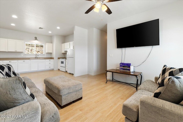 living area with a ceiling fan, light wood-type flooring, recessed lighting, and baseboards