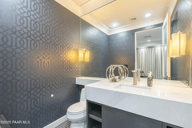 bathroom with toilet, vanity, and ornamental molding