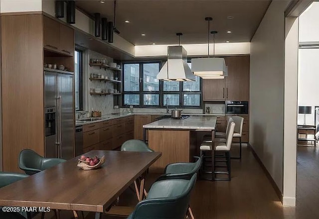 kitchen featuring built in fridge, island range hood, pendant lighting, a center island, and wall oven