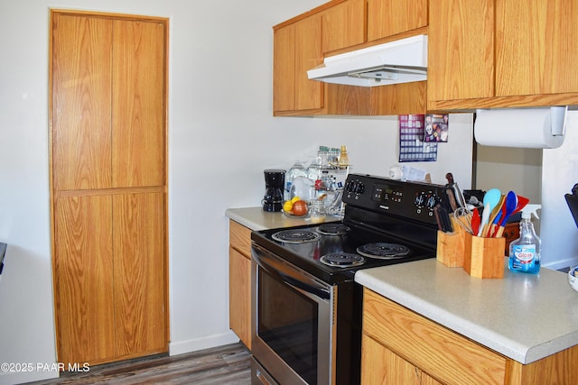 kitchen with baseboards, under cabinet range hood, stainless steel electric stove, light countertops, and wood finished floors