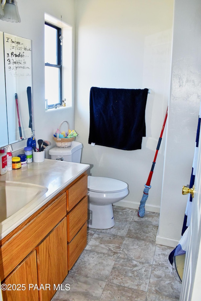 bathroom with baseboards, toilet, and vanity