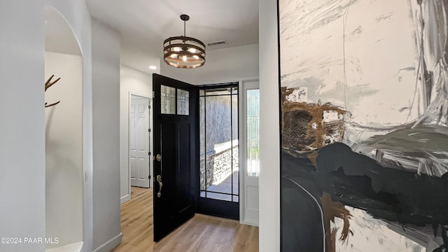 foyer featuring light wood-type flooring and an inviting chandelier