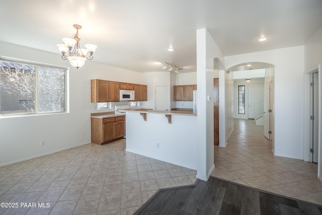 kitchen with hanging light fixtures, a notable chandelier, a kitchen breakfast bar, and light tile patterned flooring