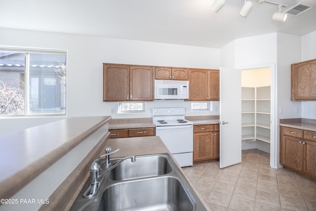 kitchen with white appliances, a wealth of natural light, sink, and light tile patterned floors