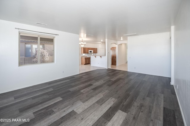 1891 N Tin Strap Trl, Prescott Valley, AZ 86314 - unfurnished living room featuring a chandelier, arched walkways, and wood finished floors