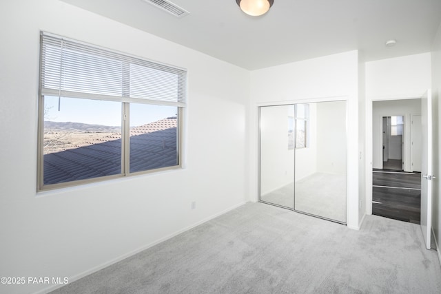 unfurnished bedroom with light carpet and a closet