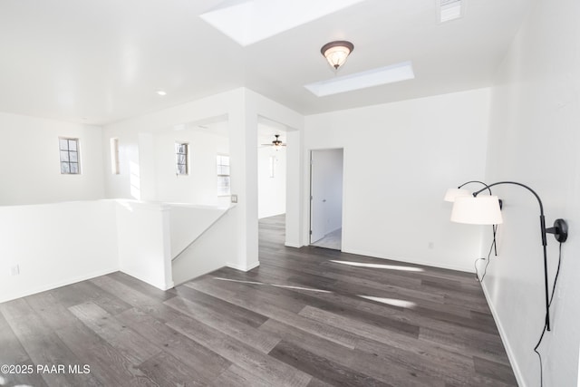 empty room featuring a skylight, dark hardwood / wood-style floors, and ceiling fan