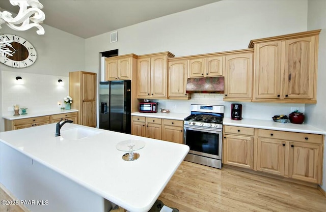 kitchen featuring a kitchen island with sink, sink, stainless steel appliances, and light wood-type flooring